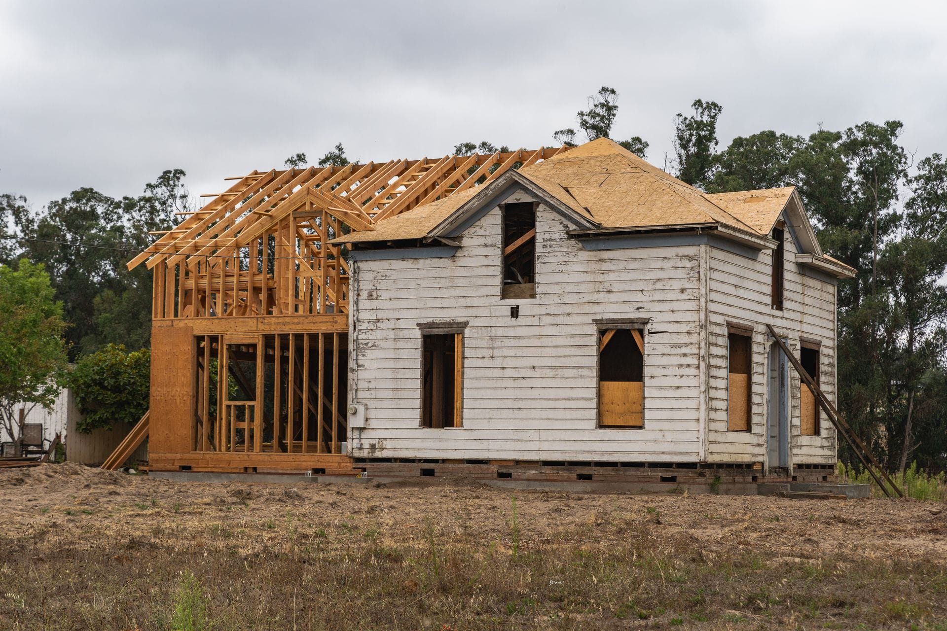 Second-storey addition being framed onto an older white clapboard farmhouse
