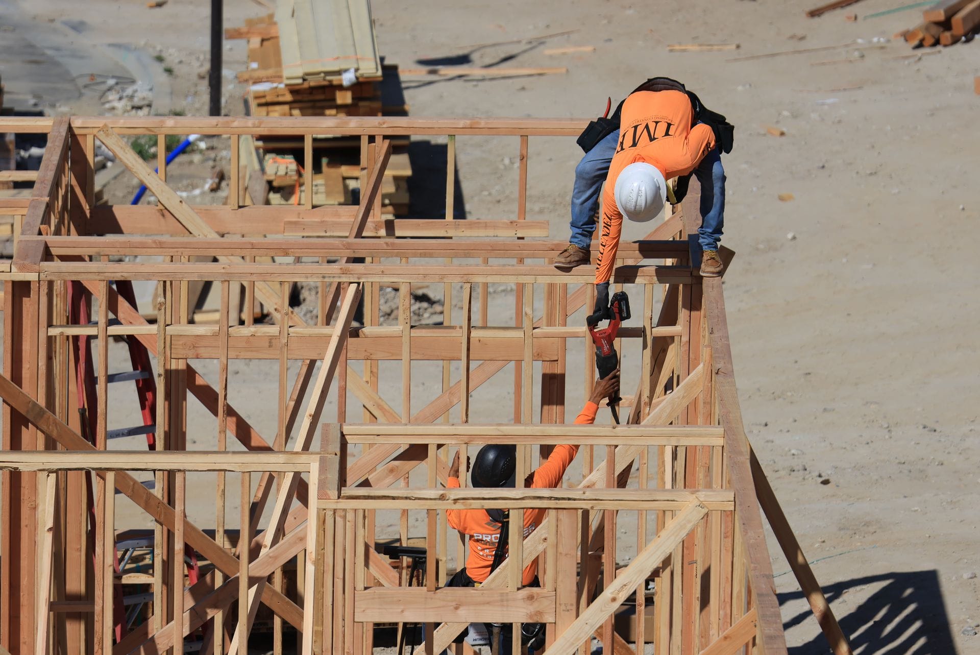 Framing crew standing and bracing stud walls on a new build, seen from above