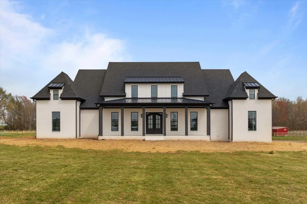 White brick farmhouse with a black metal-roofed front porch, double front doors and tall black windows