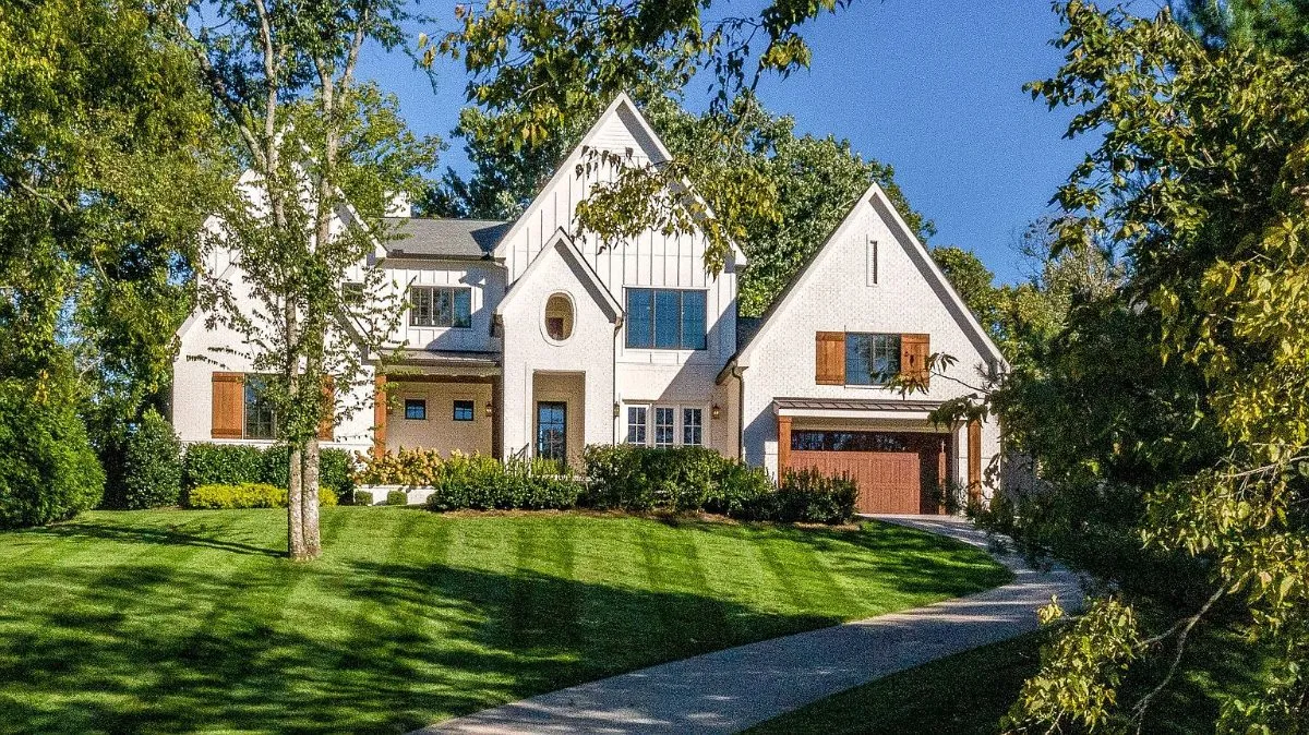 Front of the home: white brick and board-and-batten gables, cedar shutters and a cedar garage door