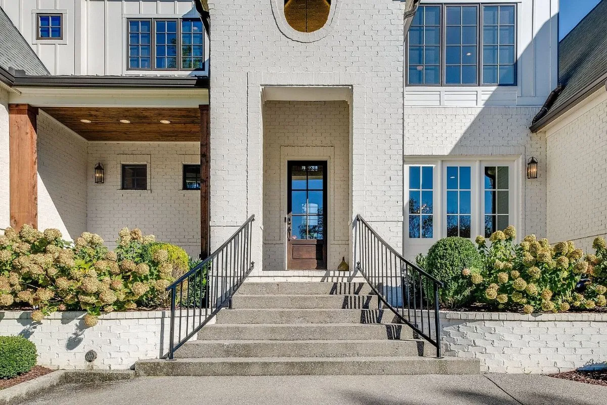 Front entry: brick stoop, iron rails and a glass-paneled door