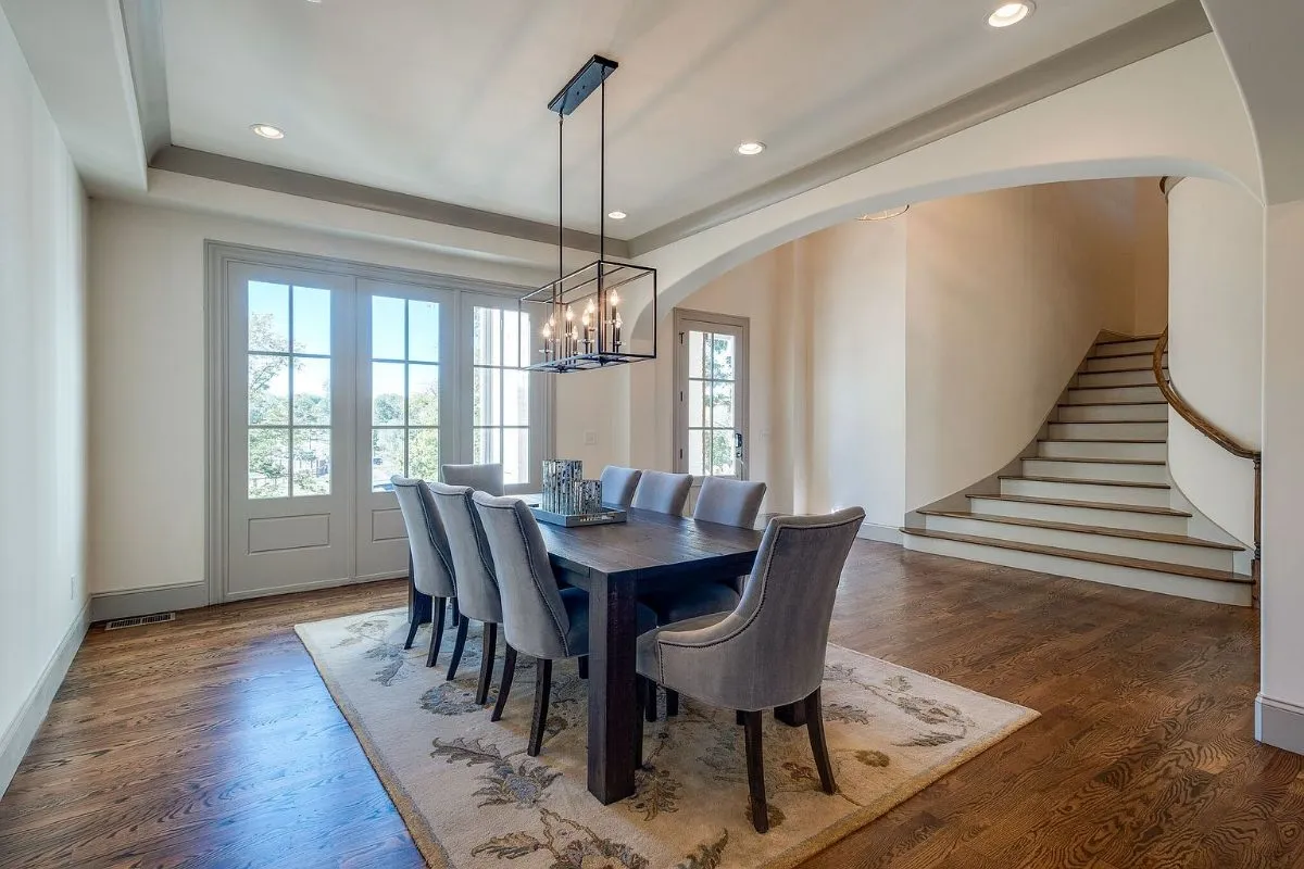 Dining room under a lantern chandelier, beside the curved staircase