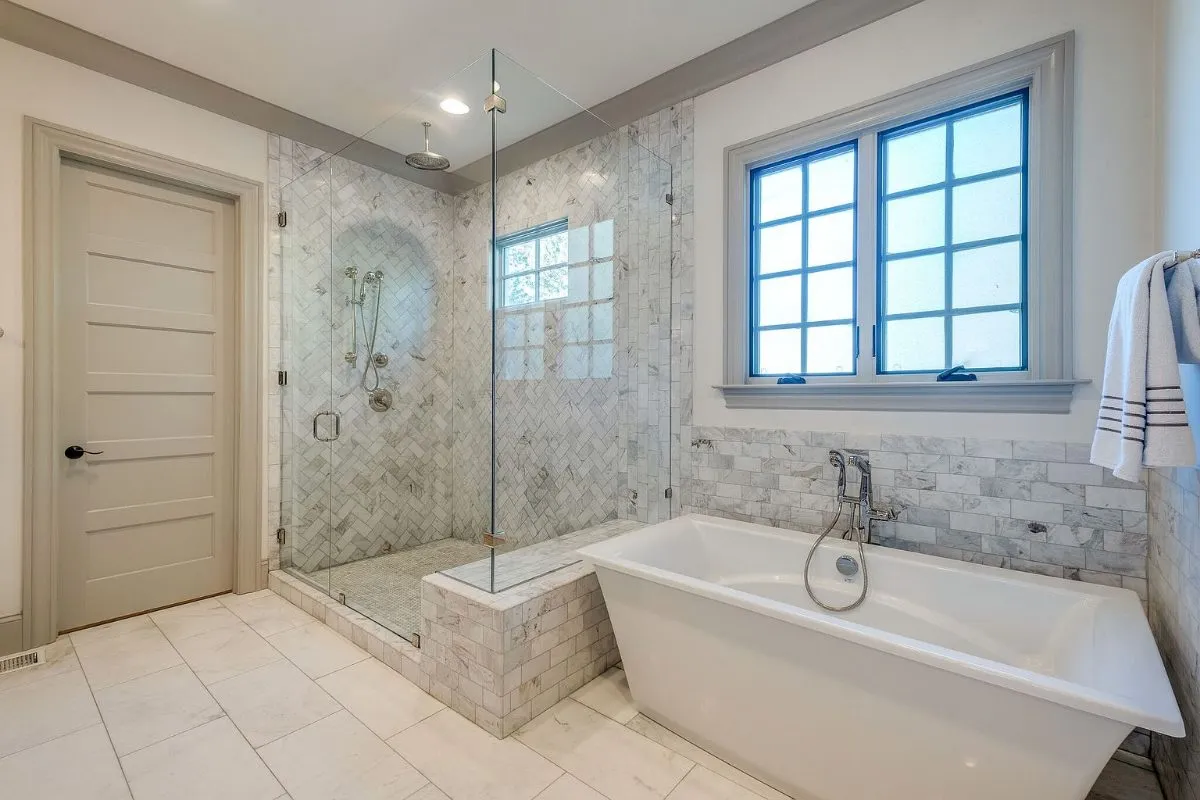 Primary bath: marble herringbone shower and a freestanding tub