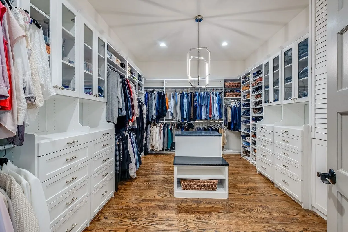 Primary walk-in closet with built-in drawers and an island