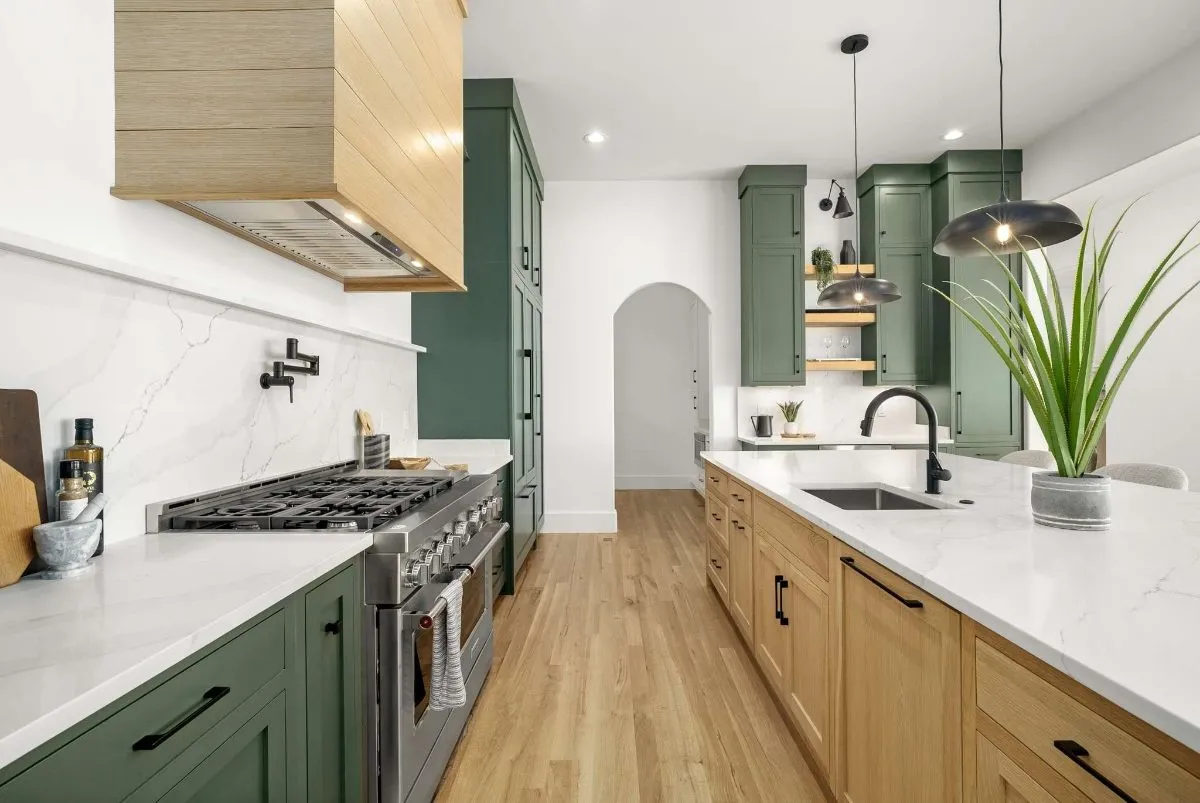 Range wall with a white oak hood and green cabinets
